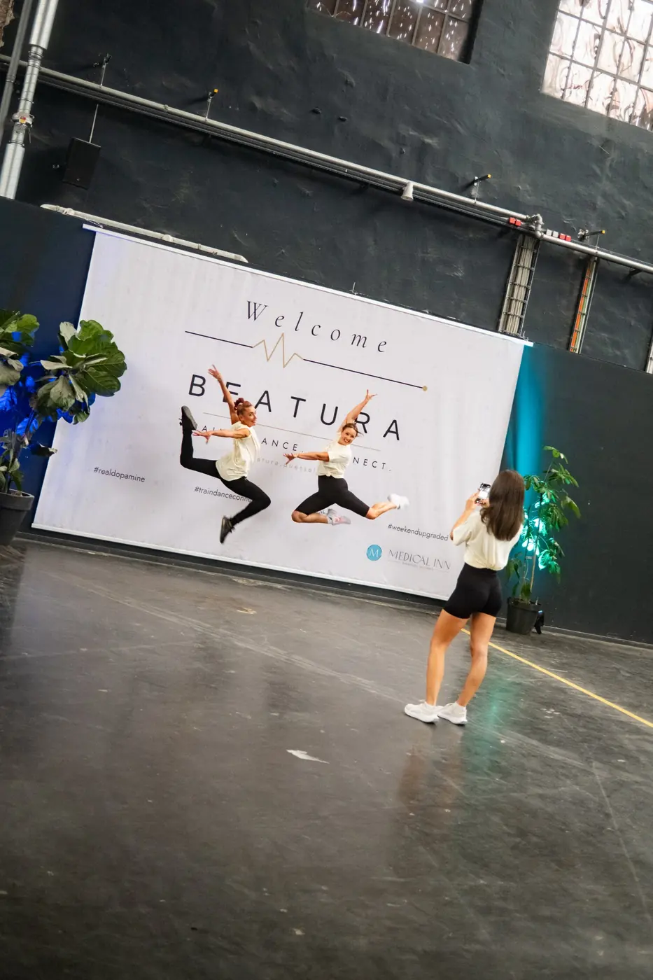 Zwei Frauen springen vor der Welcome-Wand von Beatura in die Luft